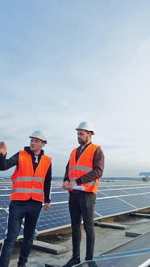 Technologien zur Solarerzeugung. Ingenieure stehen auf einem Flachdach mit vielen Sonnenkollektoren.