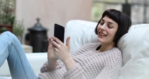 Woman Relaxing on Couch Using Mobile Phone