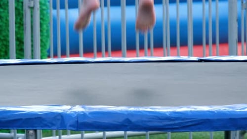 Slow motion of a little girl jumping on a big trampoline in the park.