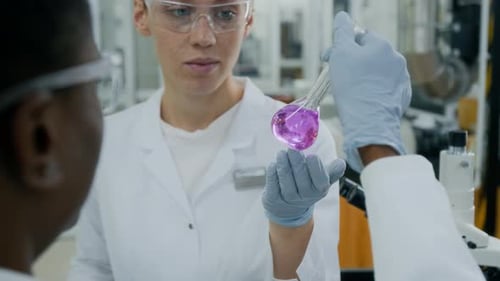 Scientists Discussing Purple Liquid Solution in Laboratory