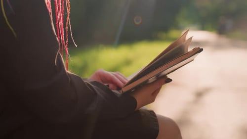Person Reading Memoir on Bench By Sunlit Path Silhouette and Hair Strands Illuminated Gentle Lens