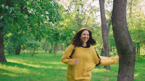 A Couple Runs Playfully Through the Park Weaving Between Trees As the Man Tries to Catch the Woman