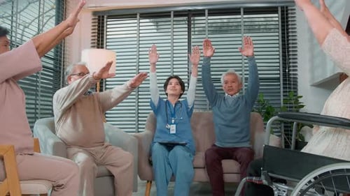 Seniors Exercising With Caregiver at Assisted Living Facility