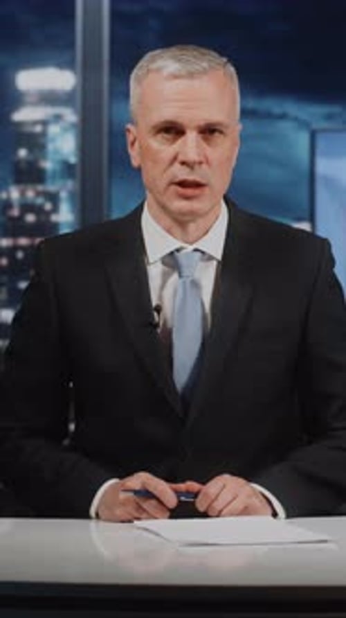 Presentador masculino maduro centrado que ofrece un reportaje de noticias de última hora en vivo en un estudio de televisión