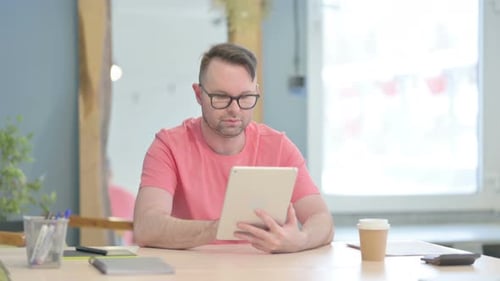 Man Uses Tablet at Workplace Desk