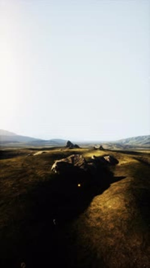 Grassy Field With Rocks and Hills