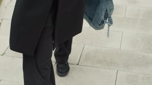 Walking Legs With Denim Backpack on City Sidewalk