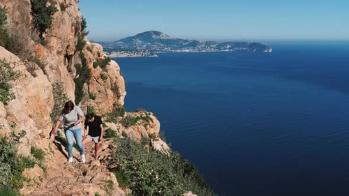 Women tourists climbing on rocky mountain