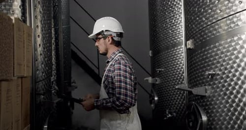Un vigneron cherche du matériel pour la distillation et la fermentation dans une fabrique de vin