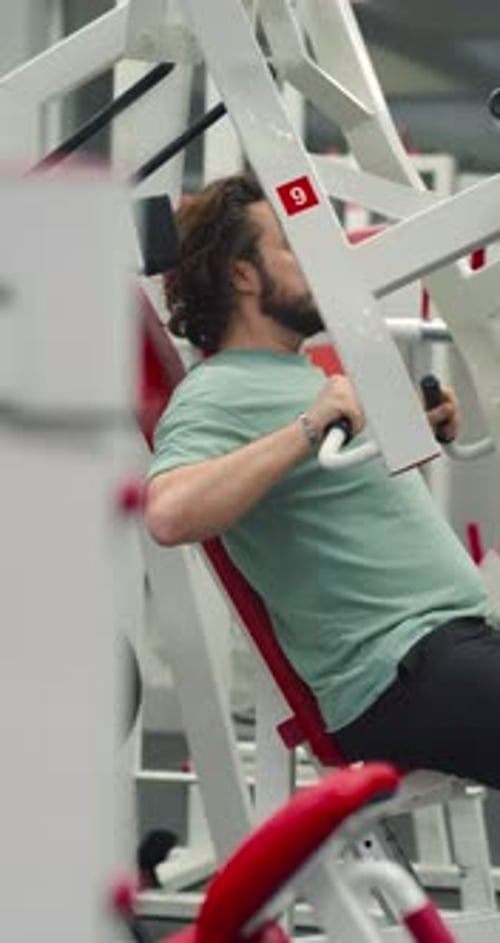 Man Working Out on Chest Press Machine at Gym