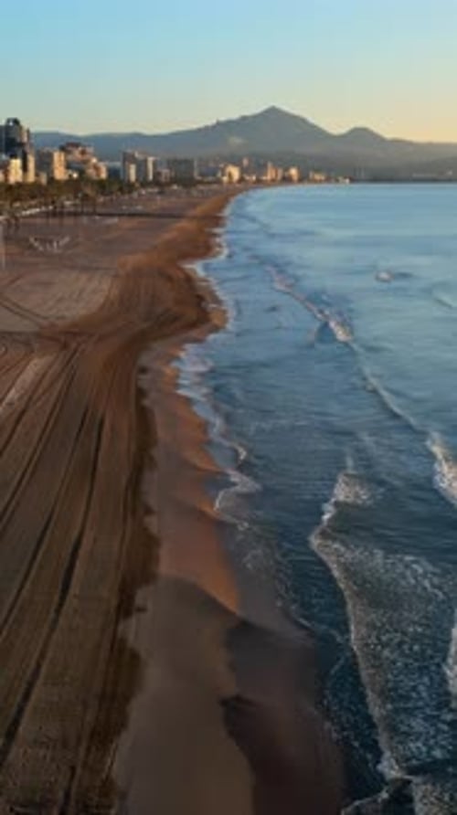 Aerial drone view of the Mediterranean Sea and the city of Alicante, Spain at sunset. Vertical