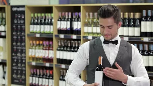 Well Dressed Man Holds Bottle of Wine and Approves