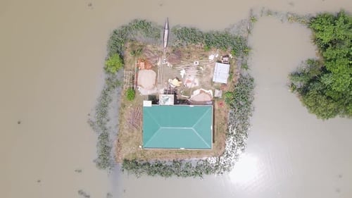 A rural home surrounded by flood water in Bangladesh. Aerial top down shot