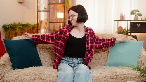 Smiling Woman Arranging Decorative Pillows at Home Satisfaction While Admiring Clean Living Space