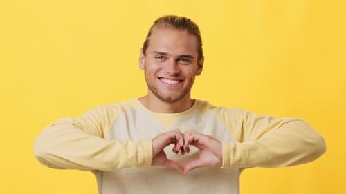 Young Man Smiling Making Heart Shape with Hands