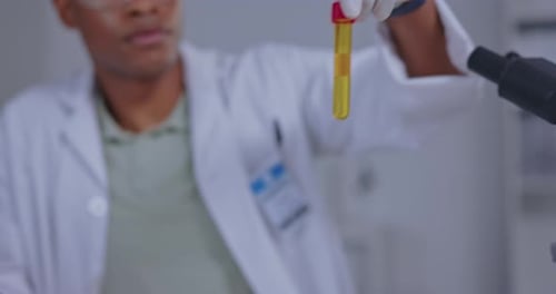 Scientist Holding Vial of Golden Liquid in Lab
