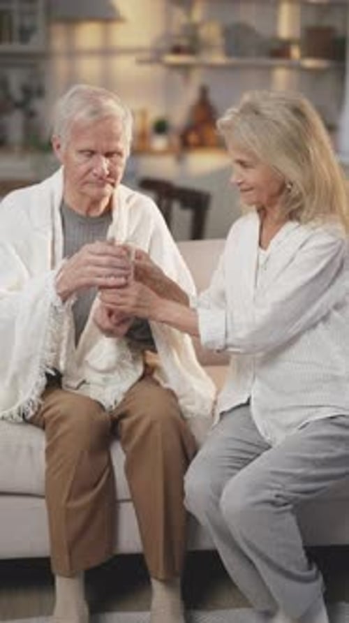 Woman Giving Medicine and Water to Senior Man