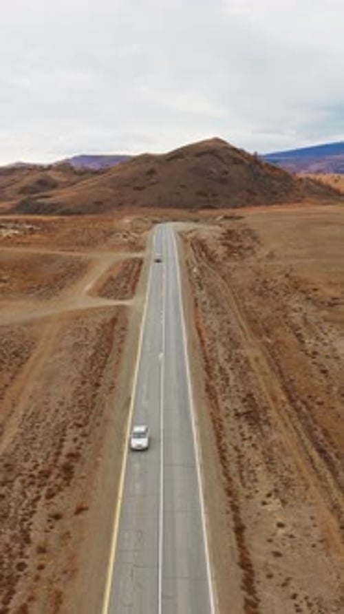 Scenic Drive Through Arid Landscape with Winding Road and Distant Hills