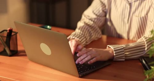 Woman working with laptop at wooden table indoors, closeup. Camera moving forward