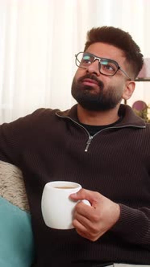 Man Relaxing on Sofa Sipping Coffee