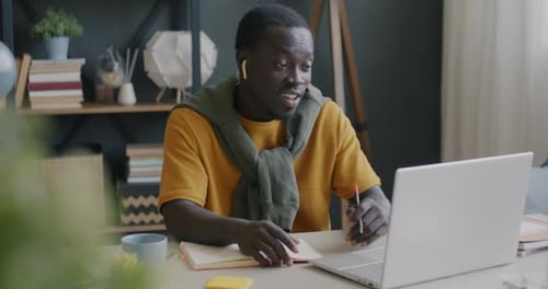 Young Adult Engaged in Virtual Meeting from Home Office