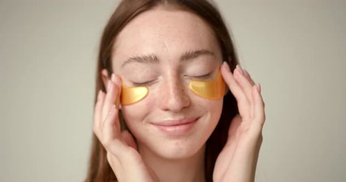 Woman Applies Gold Eye Patches for Skin Care