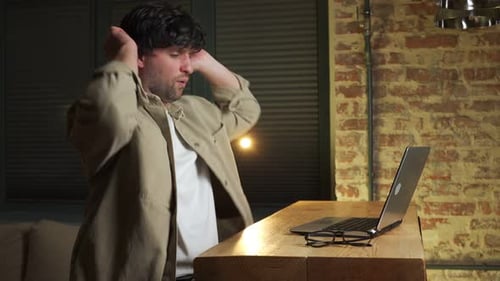 Man Working on Laptop and Relaxing at Desk