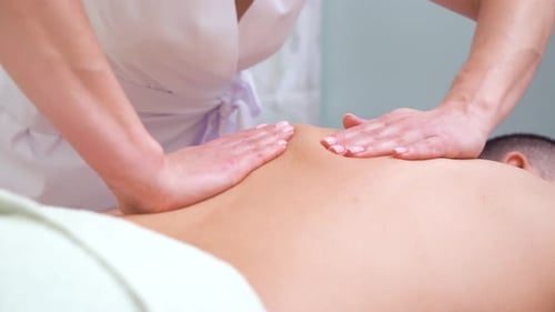 female hands doing relaxing back massage for male customer in spa salon
