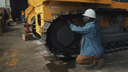 Mechanic Repairing Wheel Loader at Plant
