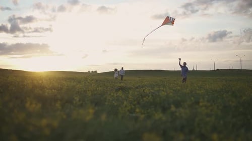 Young Family in a Outdoor Recreation a Boy with His Parents Running Through the Field Launching a