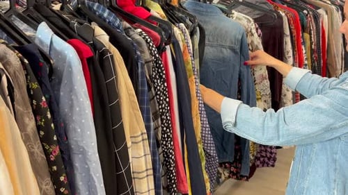 Eine Frau in einem Geschäft schaut sich Kleidung zu einem günstigen Preis an Herbstrabatte für den Verkauf von Kleidung