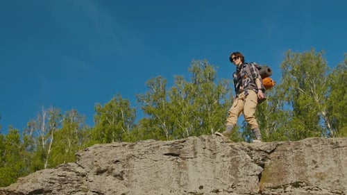 Young Woman Looking around while Standing on Hill during Summer Hiking