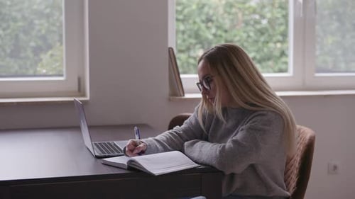 Woman Works From Home With Laptop And Notebook