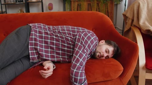 Exhausted Young Alcoholic Drunk Man Flopped Down on Couch Falls Asleep After Party Tired Overworked