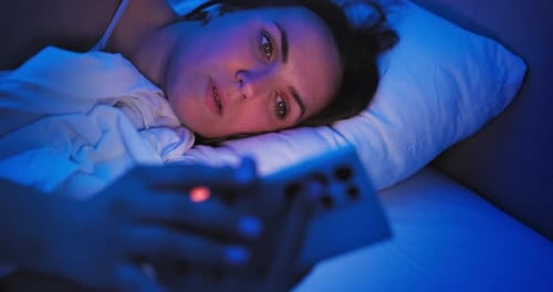 Woman Looks at Phone in Bed at Night