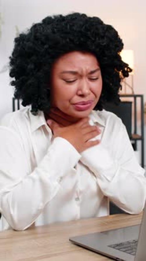 Woman with Sore Throat Using Laptop in Office