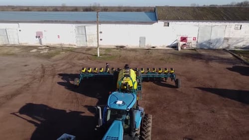 Blue tractor with yellow seeder working on the field in Ukraine OA