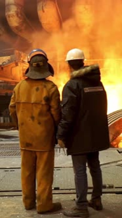 Steelworkers Standing Near a Blast Furnace with Sparks at the Metallurgical Plant Heavy Industry