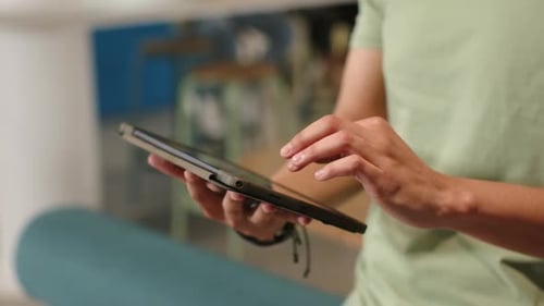 Homem adulto está tocando e deslizando o tablet em um lounge casual depois de ajustar a alça para explorar o conteúdo