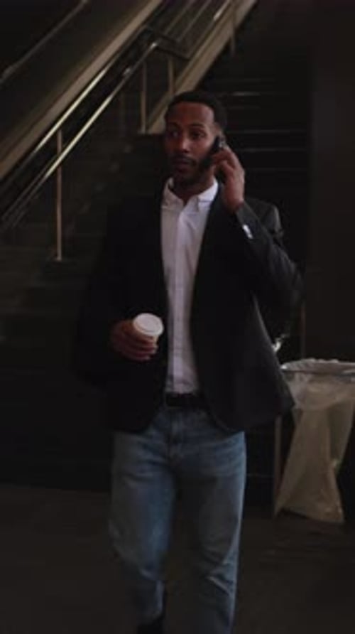 Businessman Walking and Talking on Phone in Subway Station