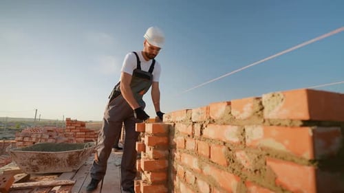 Builder Laying Bricks on Construction Site
