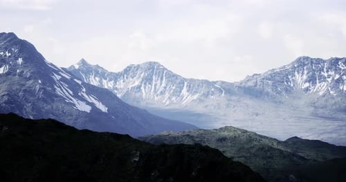 Majestic Snow Capped Mountains Rise Under a Cloudy Sky in the Afternoon Light