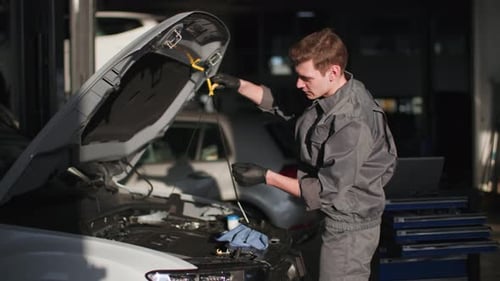 Mechanic Checking Car Oil in Garage