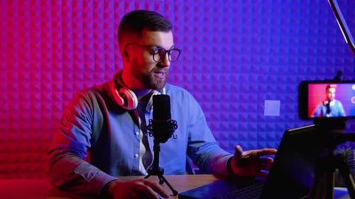 Man Broadcasting Live with Microphone and Laptop