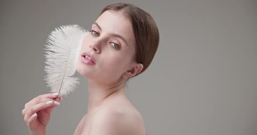 Elegant Woman Holding Feather in Studio Close Up