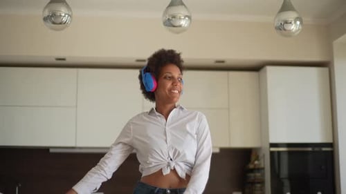 Side View of Cheerful AfricanAmerican Young Woman Wearing Headphones Dancing and Singing with Closed