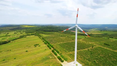 A working windmill in a field. Cloudy weather, a lot of greenery around it
