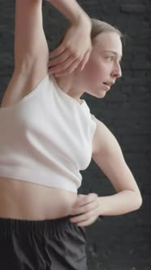Girl Dancing in Dark Studio in Front of Brick Wall