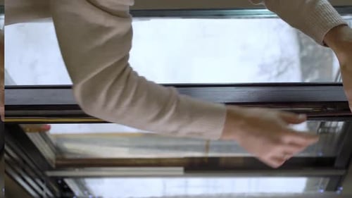 Preparando-se para a estação fria Uma mulher cola uma fita de vedação de borracha escura em uma janela interna