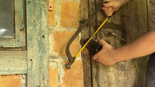 Man Cuts Padlock With Hand Saw on Door